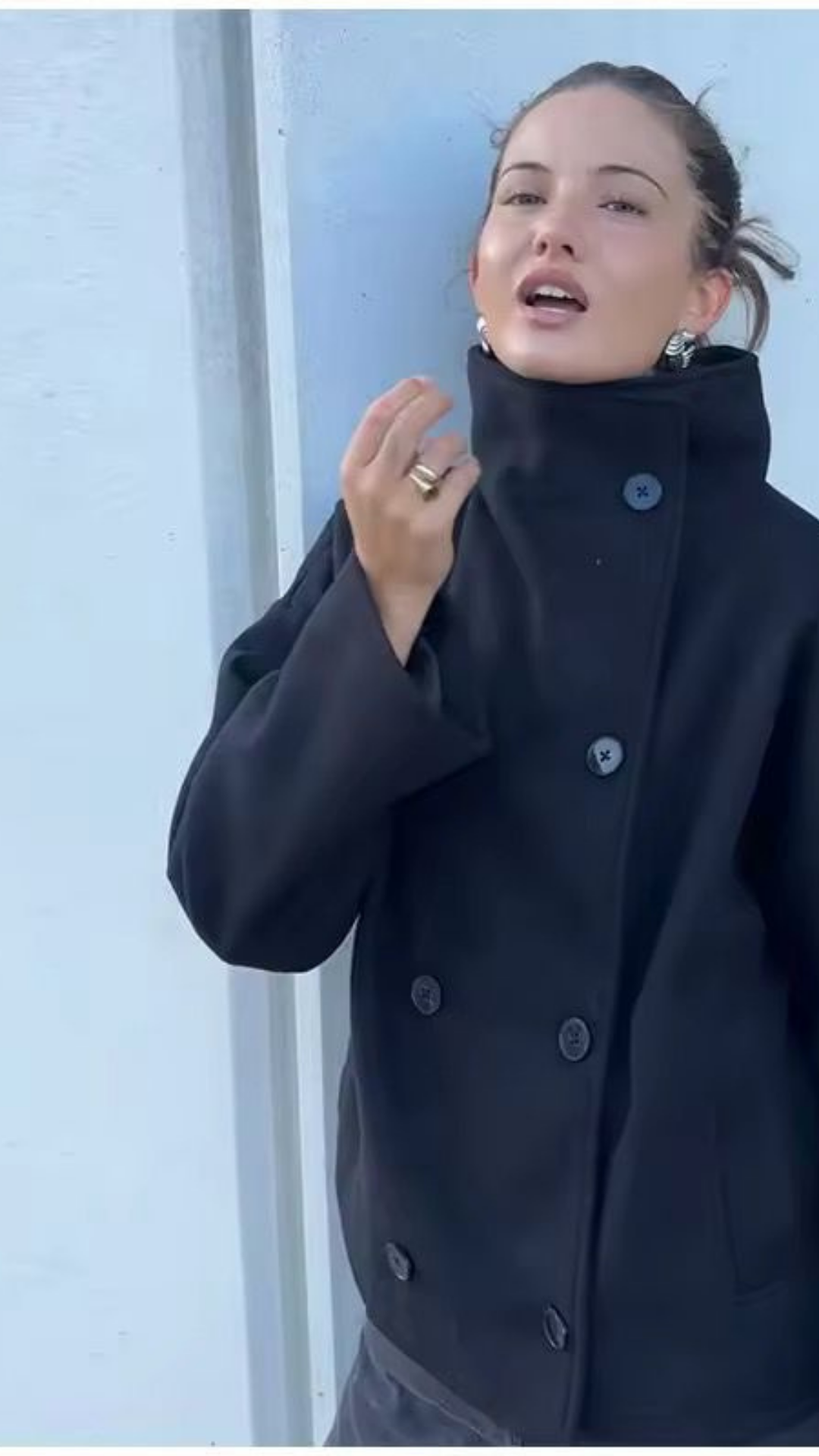 Person wearing a dark coat against a light blue background
