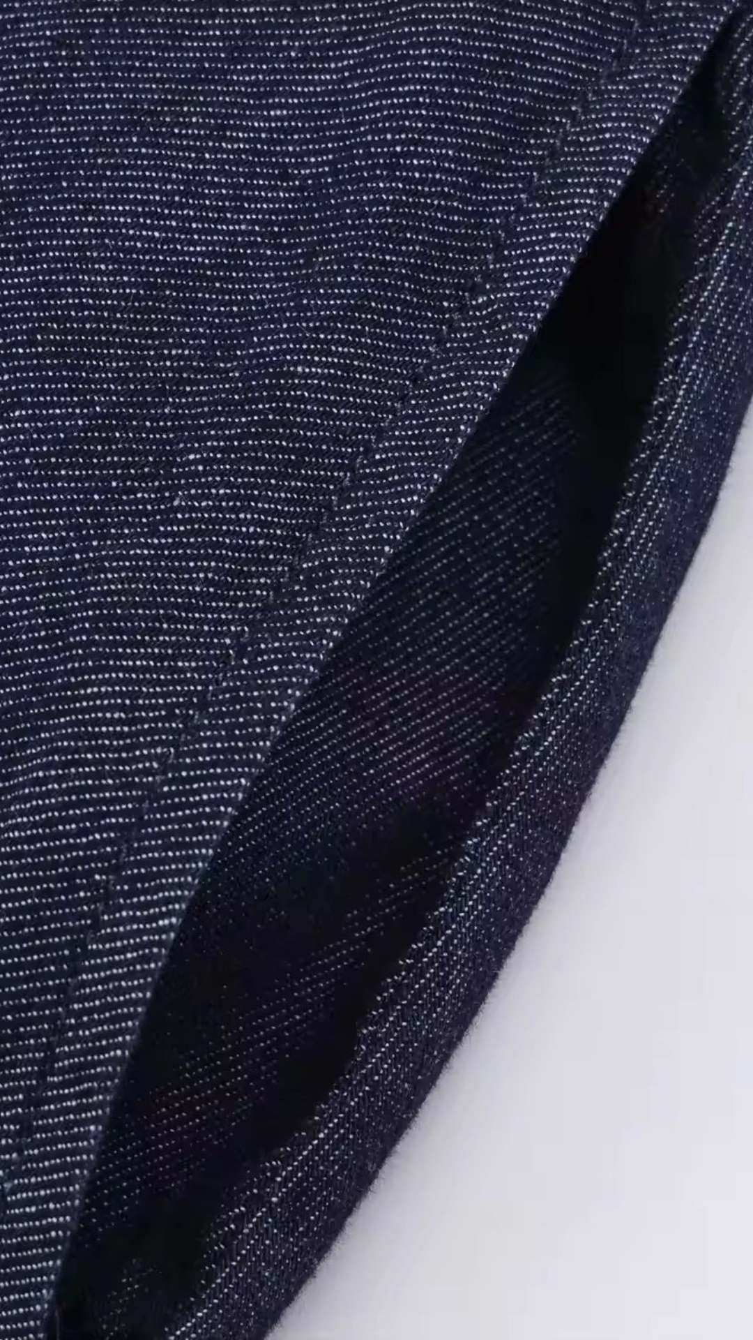 Close-up of dark blue denim fabric on a white background