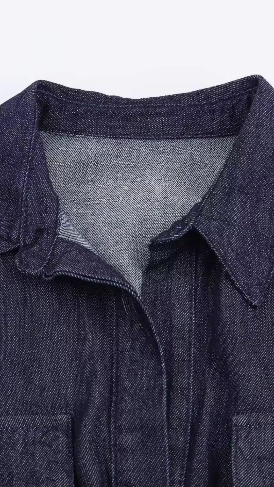 Close-up of a dark denim shirt with a gray collar on a white background